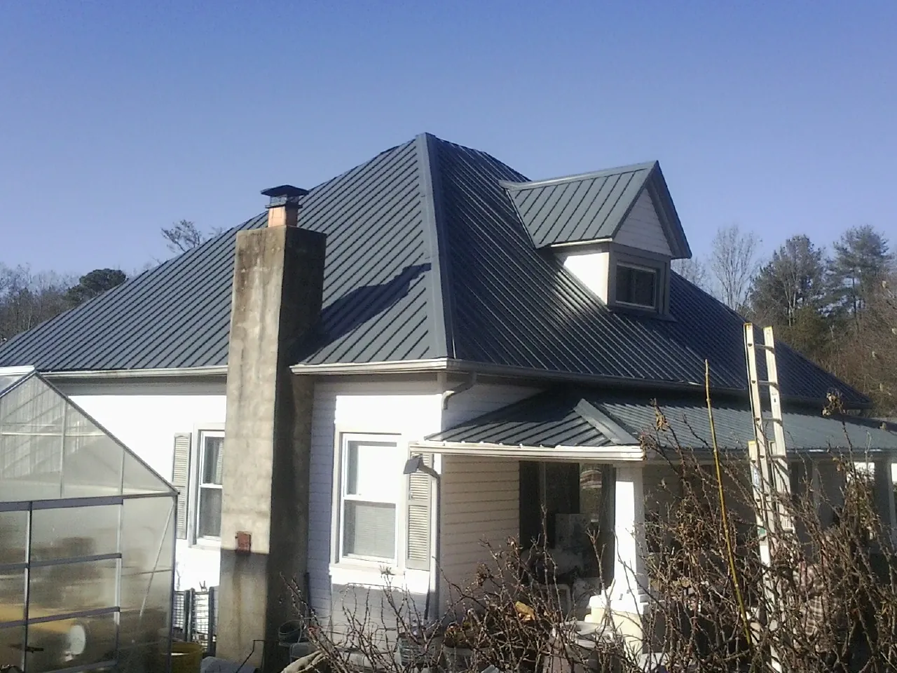 Dark blue standing seam metal roof on a white farmhouse with dormer — Slate & Tile Roof Repair by Roofing Brothers in Hestand