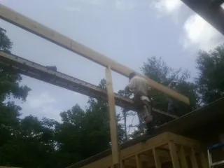 Carpenter setting a ridge beam over a new addition frame — Ice Dam Removal by Roofing Brothers in Hestand