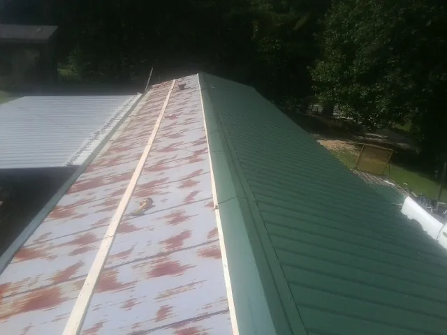 Old rusted panels beside newly installed green metal roofing — Wind Damage Roof Repair by Roofing Brothers in Hestand
