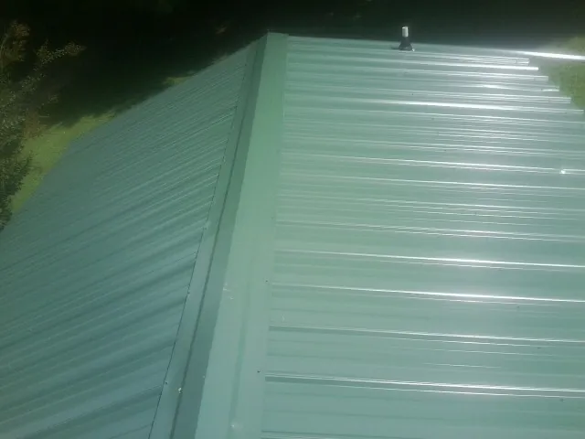 New green metal panels meeting at the ridge of a roof — Flat Roof Repair work by our crew in Hestand