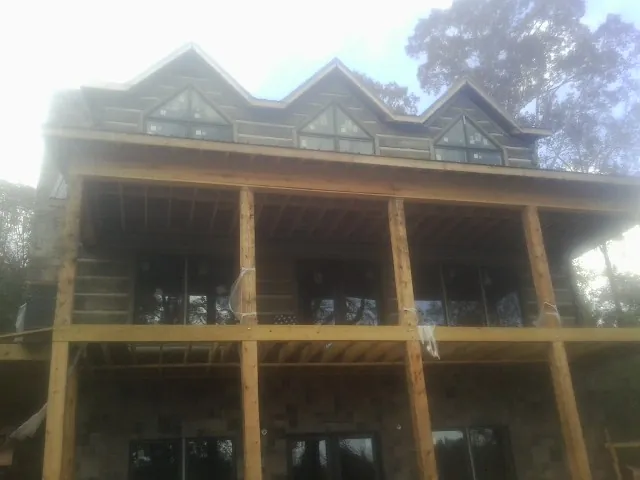 Dormers and porch framing on a large log home under construction — Roof Coating work by our crew in Hestand