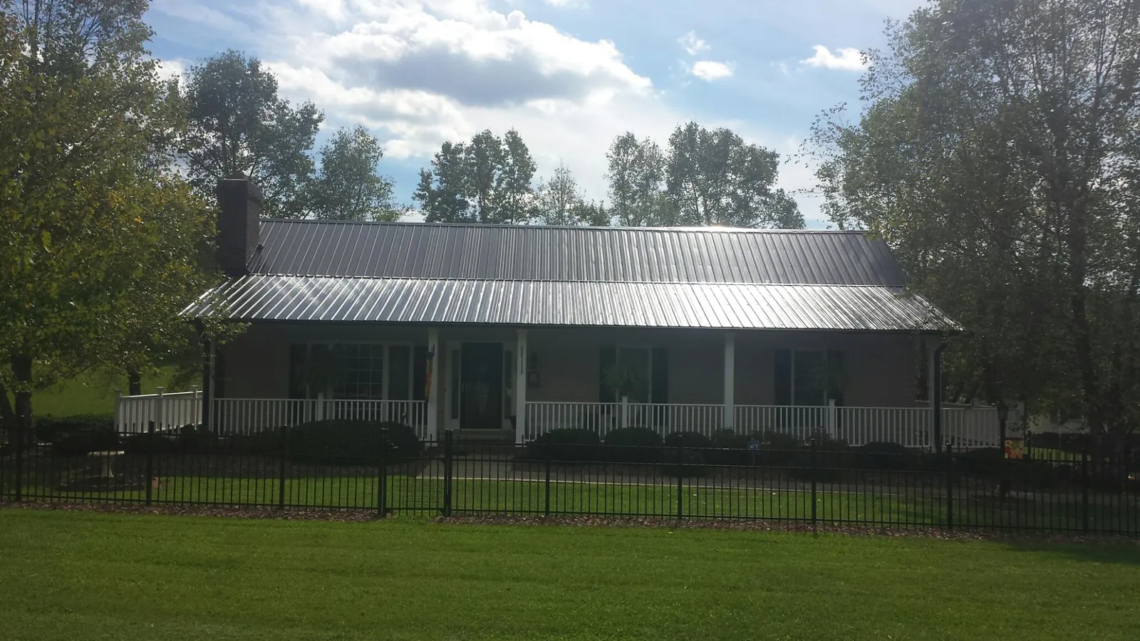 Gray metal roof on a brick ranch with a full width front porch — Gutter Guard Installation work by our crew in Hestand