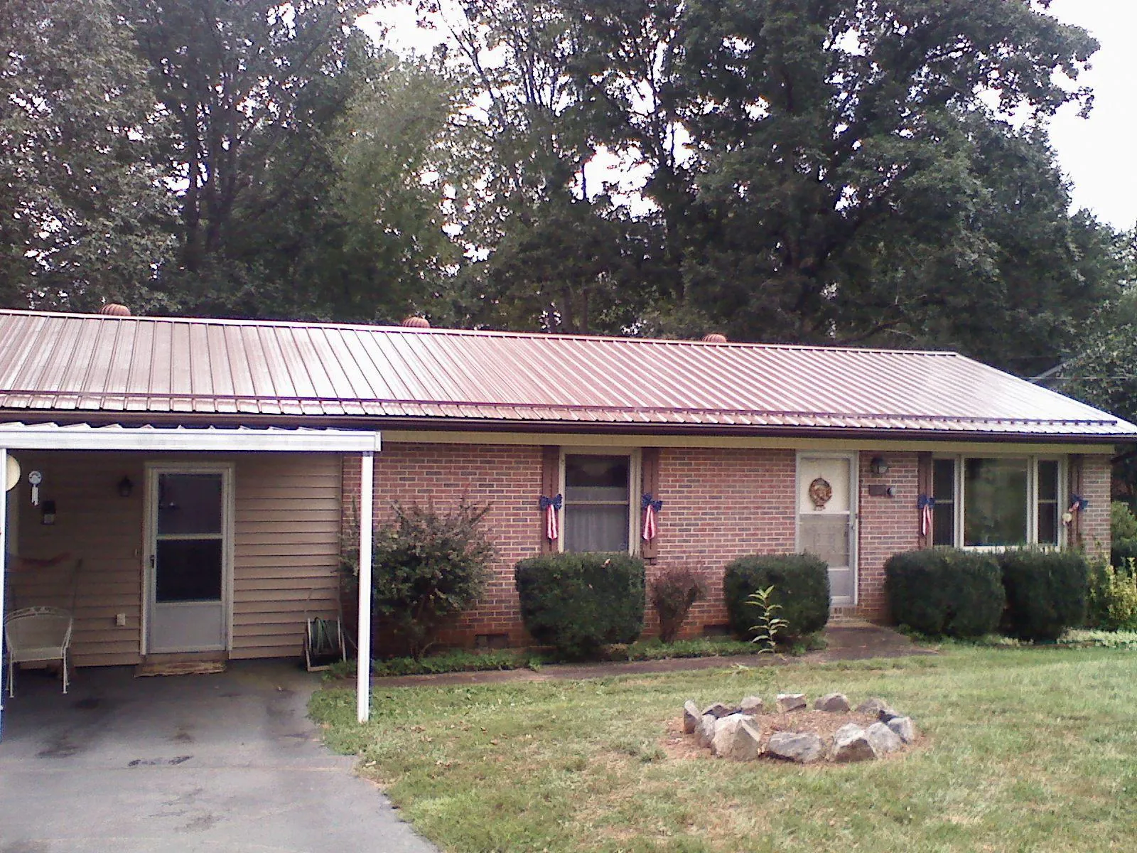 Bronze metal roof and carport on a brick ranch home — Roof Repair work by our crew in Hestand