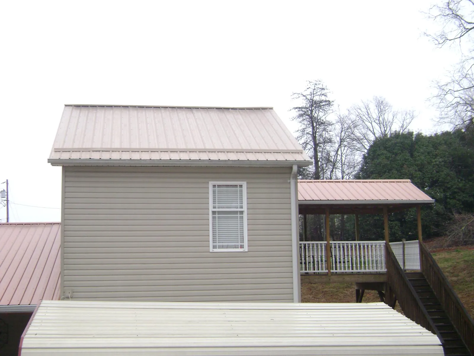 Tan metal roofs on a two story addition and attached porch, from a Roof Replacement job in Hestand