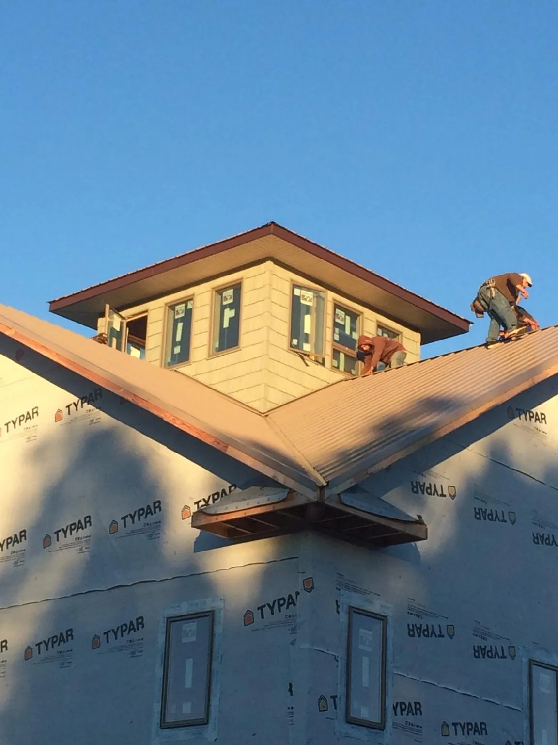 Roofers working around a rooftop cupola on a new metal roof at sunset — Roof Waterproofing in Hestand by Roofing Brothers